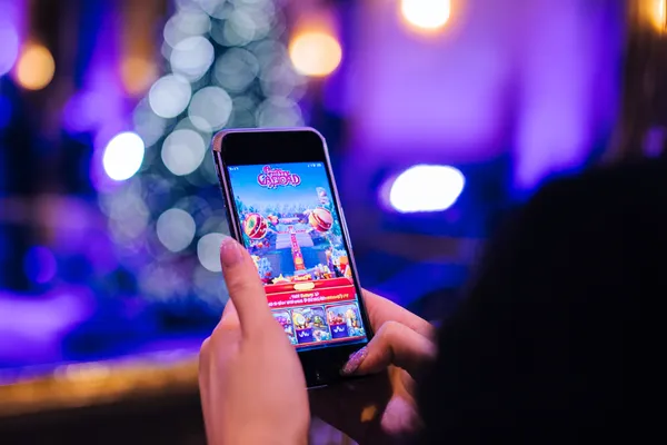 A young woman relaxing with her phone while dynamic casino elements float around her, illustrating the smooth mobile experience offered by the SOYL777 app.